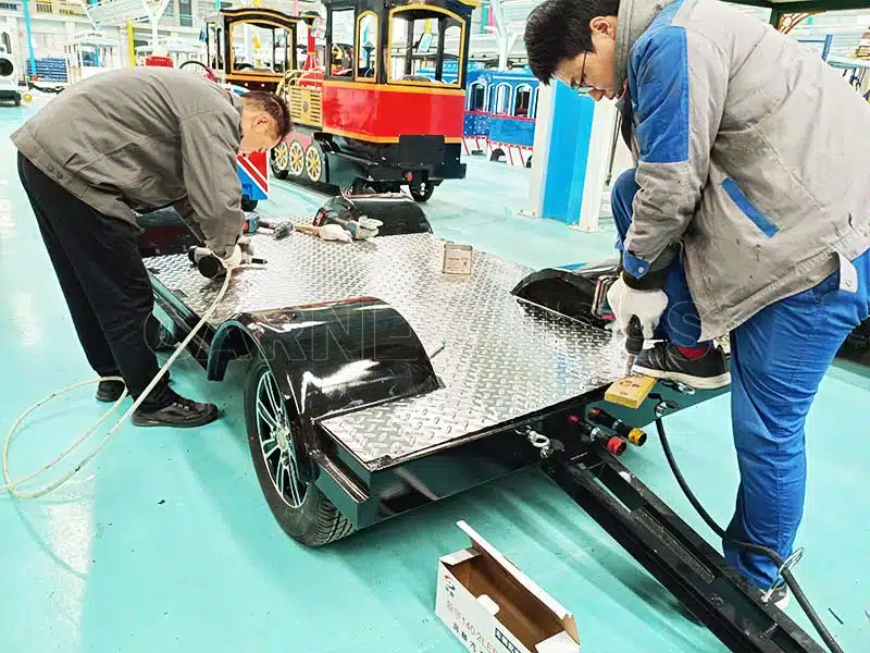 Engineers assembling components of a trackless train in Carnee Rides’ factory workshop, ensuring quality and precision.