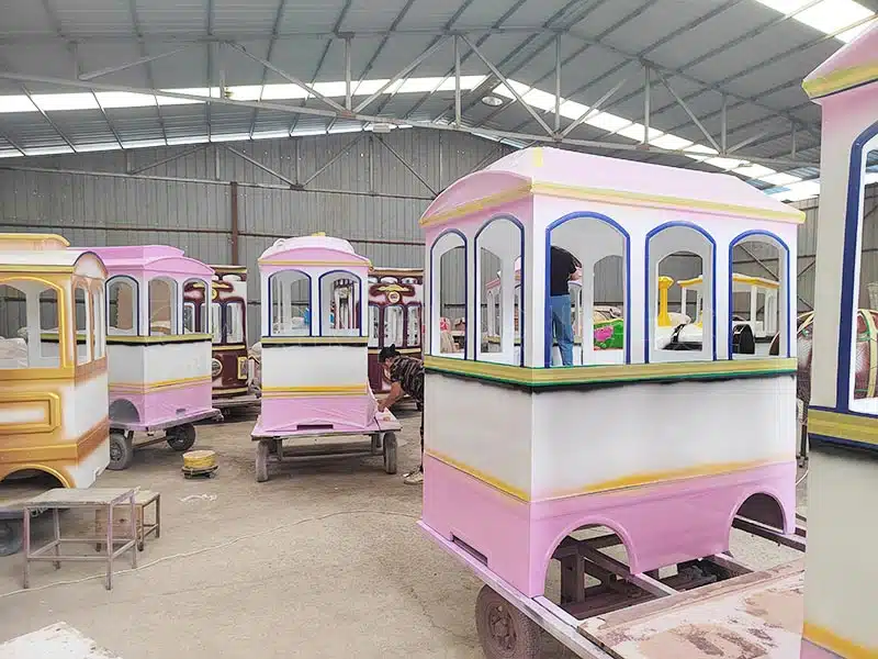 Trackless train painting process in the factory, showcasing the colorful design on carriages.