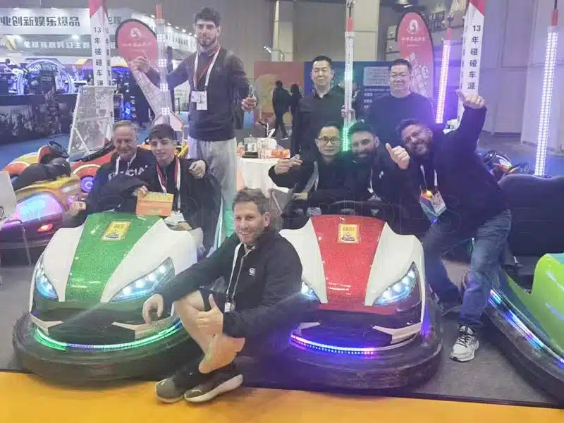 International customers test-driving electric bumper cars at an amusement ride exhibition, taking photos with the manufacturer’s team.