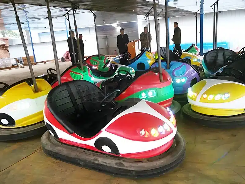 Colorful ceiling bumper cars arranged in an amusement park, showcasing various vibrant designs including red, green, and blue cars. Ideal for kids and adults, featuring interactive electric bumper car experiences under a ceiling power grid system.
