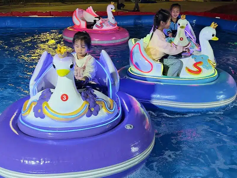 Kids enjoying commercial electric swan inflatable water bumper boats with glowing LED lights in a shallow pool, a highly profitable aquatic ride for summer carnivals and FECs.