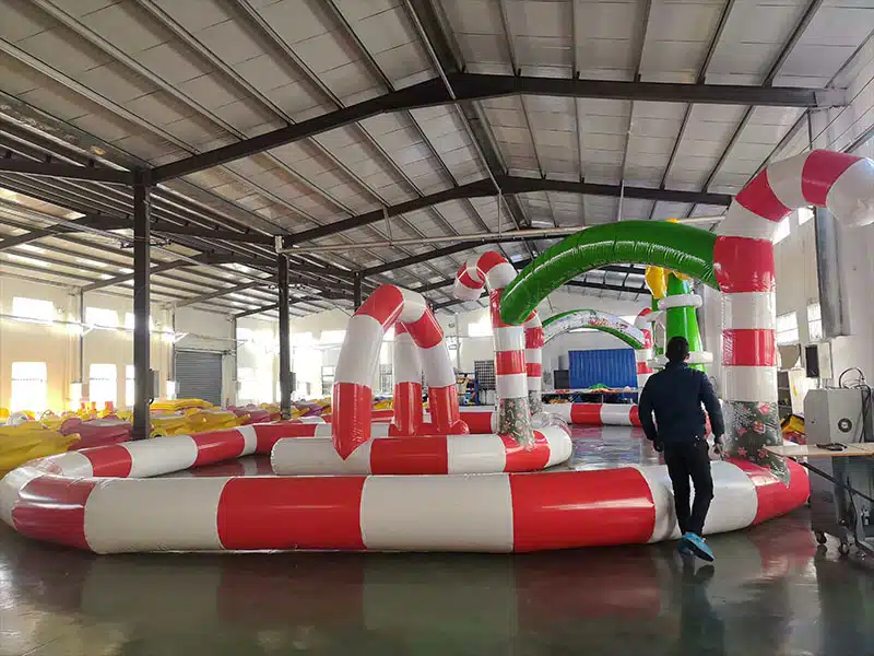 Factory setup of a large custom inflatable bumper car racing track, ideal for mobile party rental businesses and carnivals.