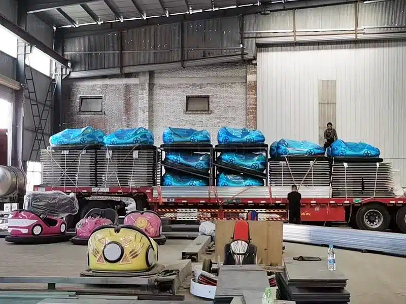 Packed ground grid bumper cars and steel floor panels prepared for shipment, displayed inside the manufacturing facility.