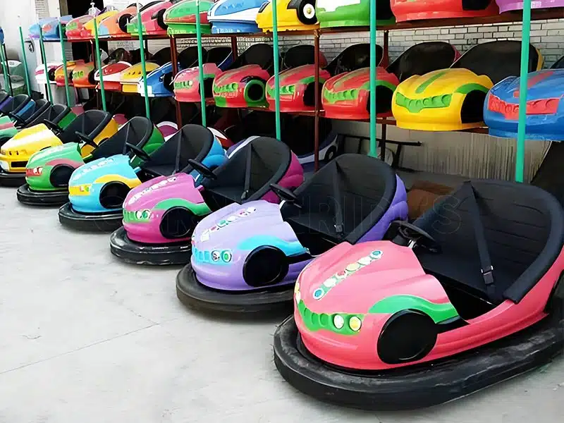 Electric ceiling bumper cars in manufacturing stage, featuring colorful body designs such as red, blue, and yellow. These cars operate using a ceiling grid power system, perfect for indoor or outdoor amusement rides.