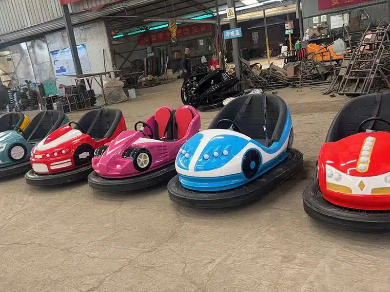 Fiberglass ground grid bumper cars lined up inside the workshop, showing various shell designs and manufacturing quality.