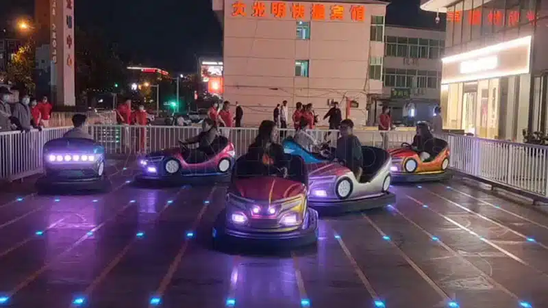 Night view of ground grid bumper car floor with LED lights and operating bumper cars on conductive grid surface.