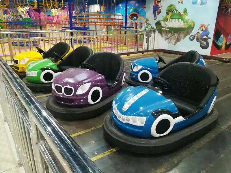 Colorful ground grid bumper cars inside an indoor bumper car arena, showing floor grid tracks and 2-seat electric dodgem cars for amusement parks.