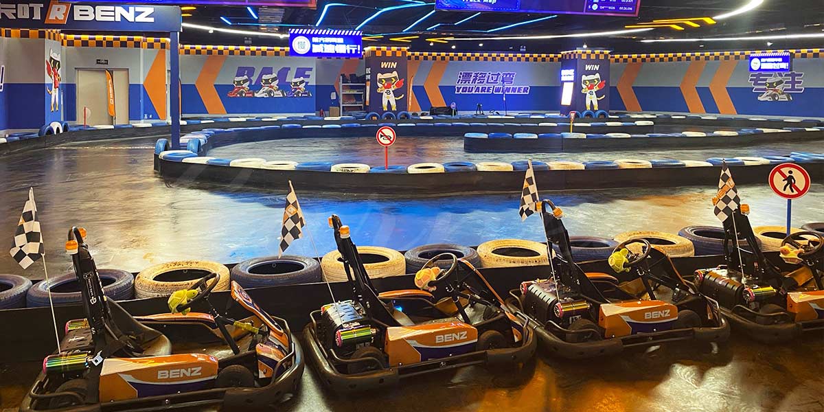 Lintasan pusat hiburan keluarga dalam ruangan (FEC) yang diterangi lampu dan menampilkan armada go-kart dewasa elektrik yang siap digunakan untuk balapan tanpa emisi.
