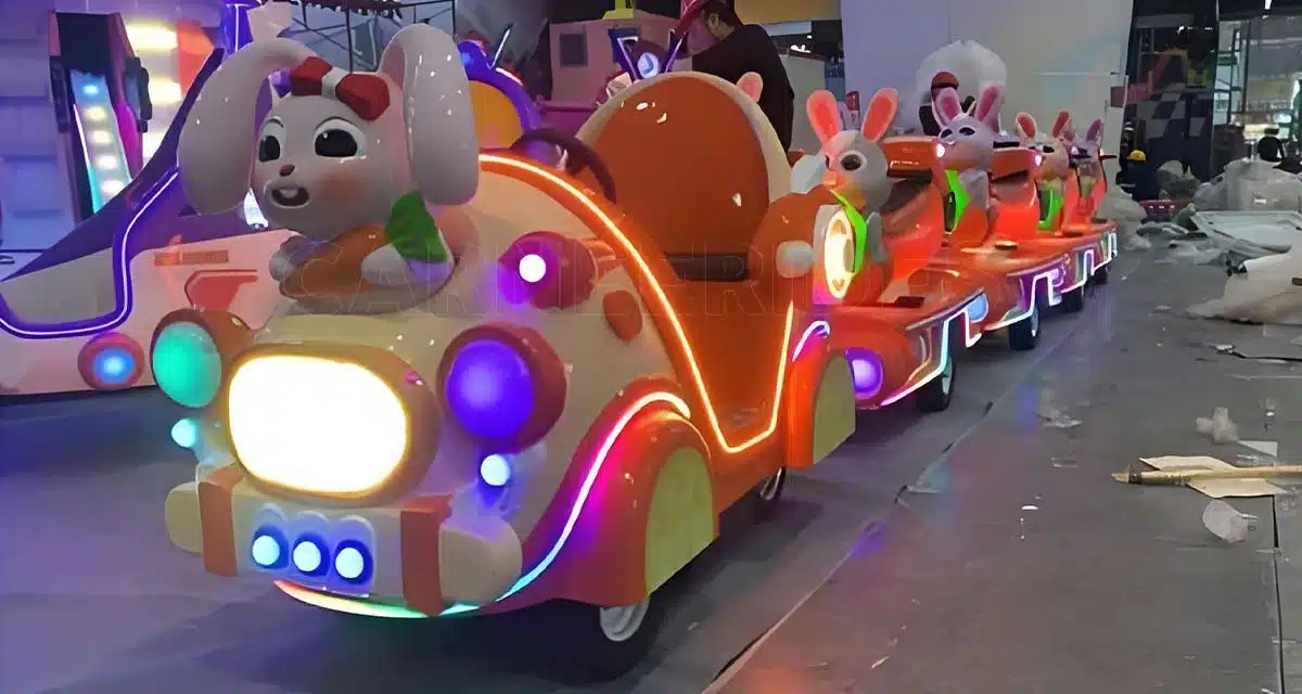 منظر جانبي لقطار كهربائي طويل أحمر اللون عتيق الطراز بدون مسار مع عربات في الهواء الطلق متوقفة في الهواء الطلق. هذا القطار الأرضي الذي يعمل بالبطاريات مثالي للنقل في المنتزهات الترفيهية ويستوعب الأطفال والكبار على حد سواء.