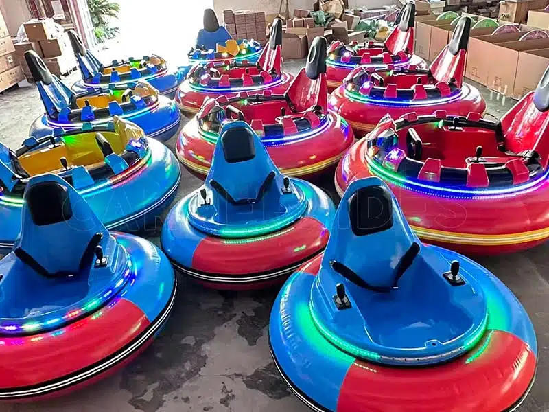 A large fleet of finished commercial new inflatable dodgems in vibrant blue and red colors, featuring dazzling LED light rings tested on the factory floor.