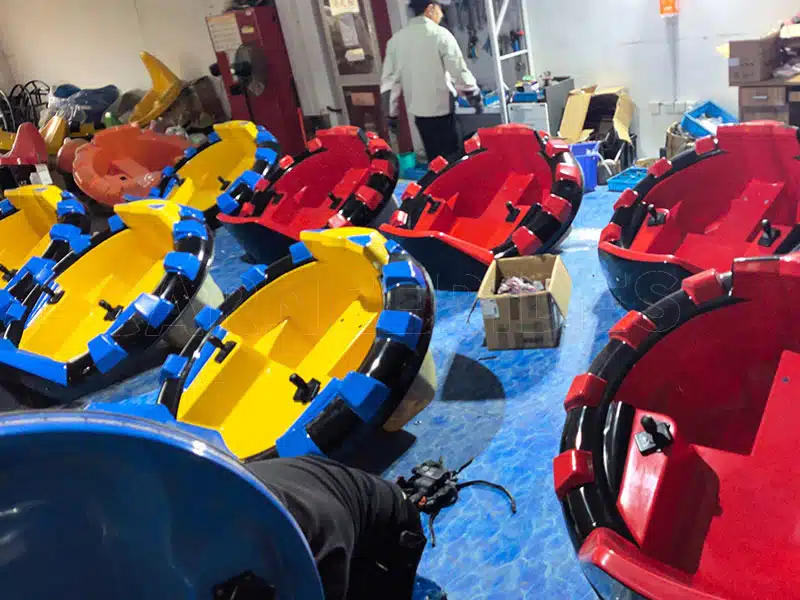Carnee Rides factory workers assembling the premium fiberglass bodies and thick anti-collision bumpers for red and yellow inflatable bumper cars.