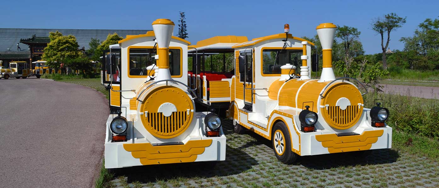 Train électrique jaune sans rail dans le parc du jardin pittoresque, train touristique alimenté par batterie, attraction écologique pour les familles dans les parcs d'attractions.