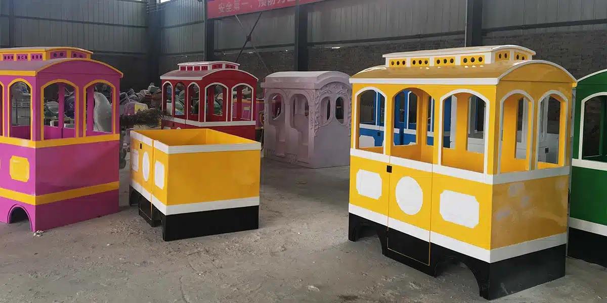 Custom trackless train carriage production in factory showing painted cabin shells before final assembly