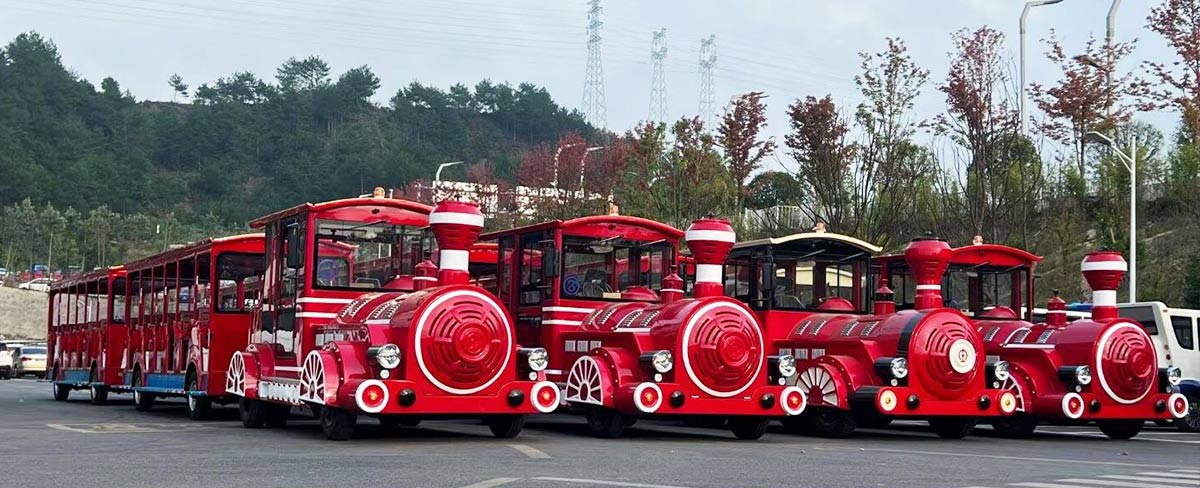 Red tourist trackless trains parked in scenic area showing large capacity sightseeing train ride options