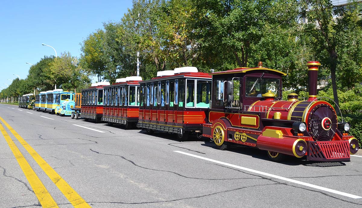 Diesel trackless tourist train with multiple passenger carriages operating on a paved road for sightseeing transportation