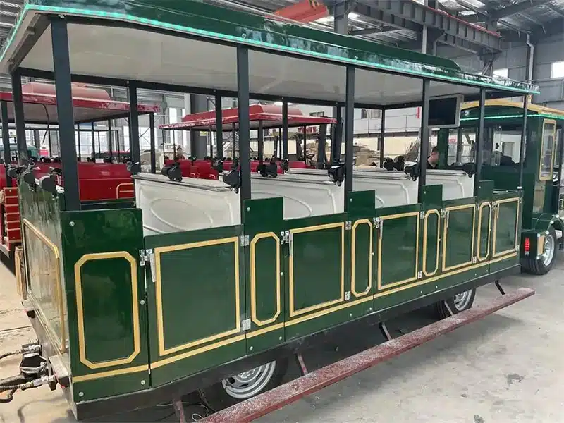 Commercial trackless train passenger carriage with open sides, seating and safety doors during factory production