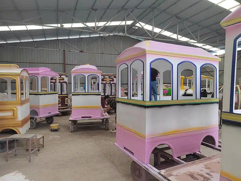 Trackless train passenger carriages undergoing painting and finishing inside the manufacturing workshop