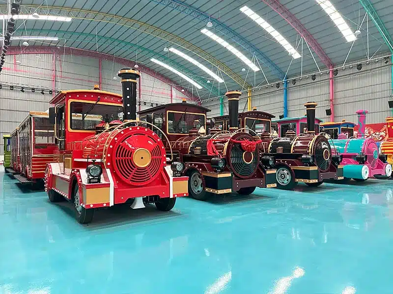Multiple finished commercial trackless trains lined up inside the Carnee manufacturing factory