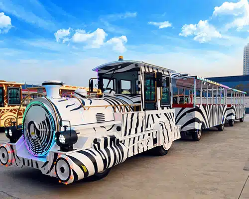 Large zebra-themed trackless tourist train with open passenger carriages for zoos and resorts
